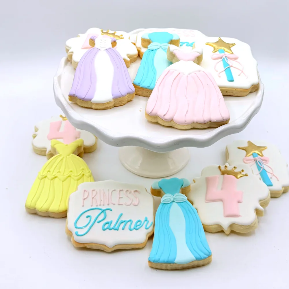 Princess party cookies with ballgowns in lavender, blue, pink and yellow, a wand, a crown and a number four