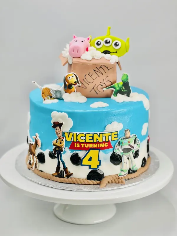 Toy Story cake with Woody, Buzz, alien and pig toppers reading Vicente is turning 4