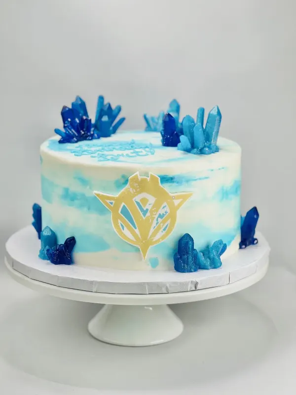 Watercolor blue cake with rock candy crystals and a gold fondant crest emblem