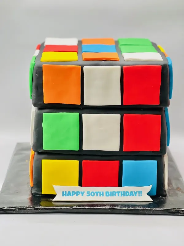 Rubik's cube birthday cake in fondant squares with a HAPPY 50TH BIRTHDAY banner