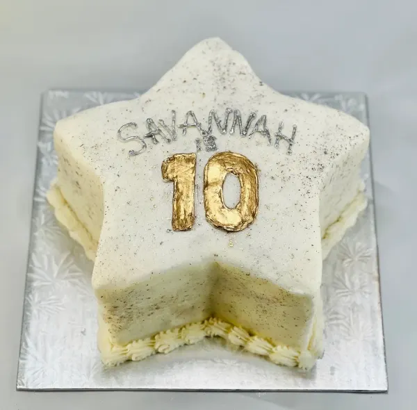 Star-shaped cake in speckled white buttercream with SAVANNAH IS 10 in silver and gold