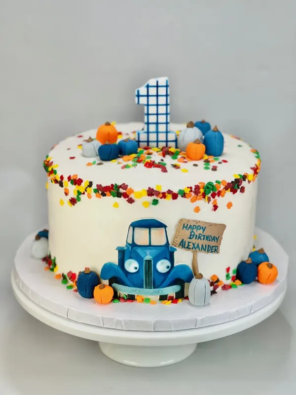 First birthday cake with a blue tractor, fondant pumpkins and Happy Birthday Alexander sign