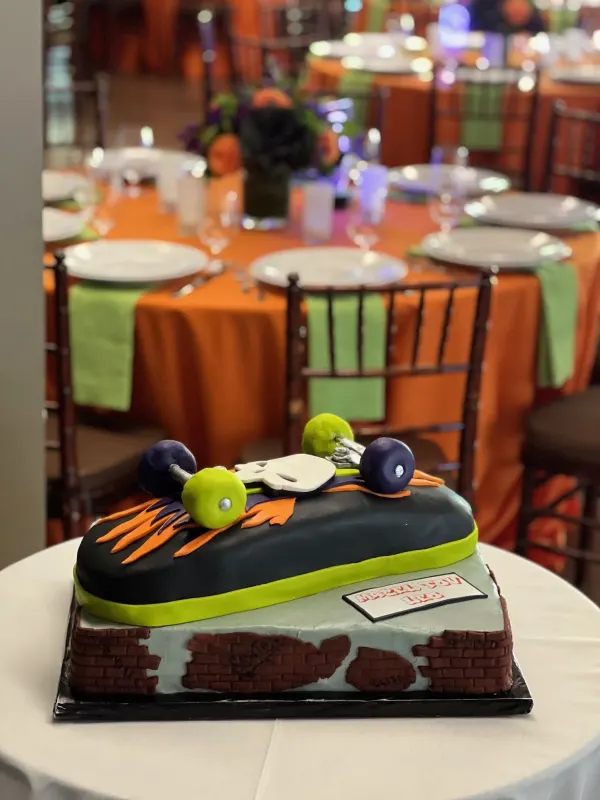 Skateboard cake on a brick-wall base with orange flames, green wheels and a skull deck