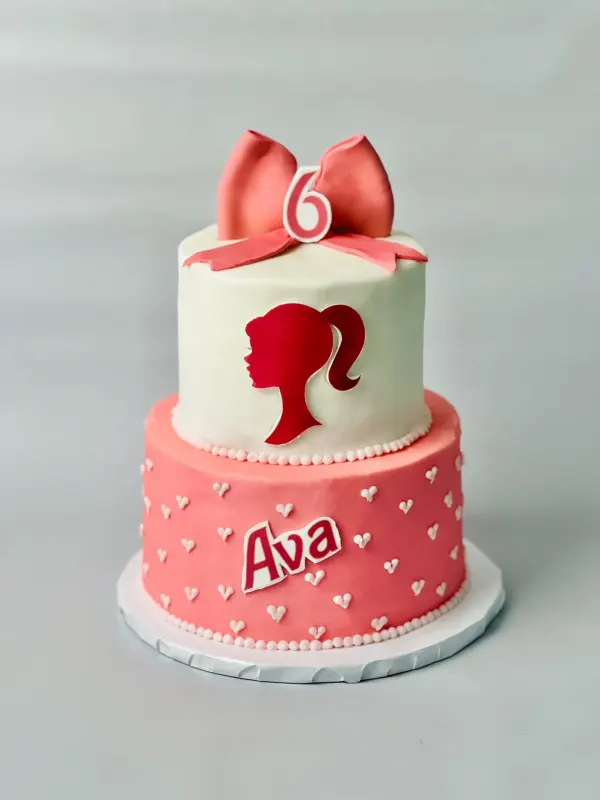 Two-tier Barbie cake with a pink silhouette, bow topper, hearts and Ava with number 6