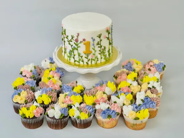 Wildflower first birthday cake with a gold number 1 and dozens of buttercream flower cupcakes