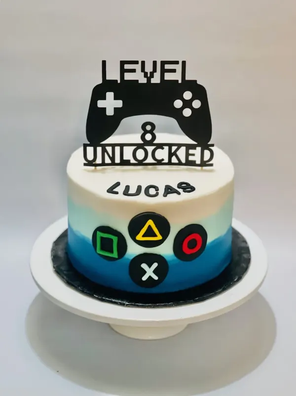 Video game birthday cake with controller buttons, the name Lucas and a Level 8 Unlocked topper