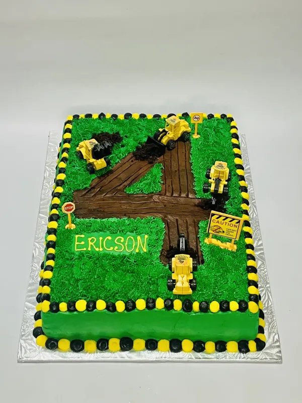 Construction sheet cake with a dirt road number 4, toy diggers and the name Ericson piped in yellow