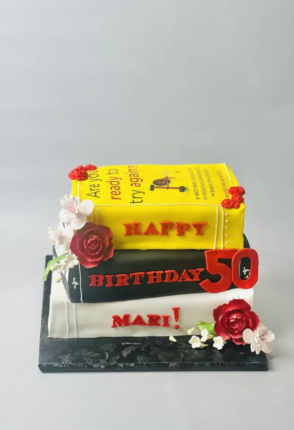 Stacked book cake with sugar roses reading Happy 50th Birthday Mari