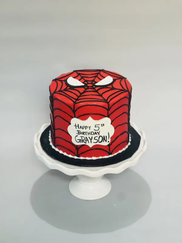 Spider-Man birthday cake with red and black web piping, white eyes and Happy 5th Birthday Grayson