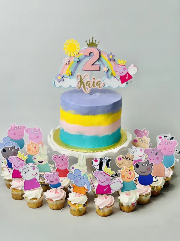 Peppa Pig cake with pastel buttercream stripes, a rainbow 2 Kaia topper and character cupcakes