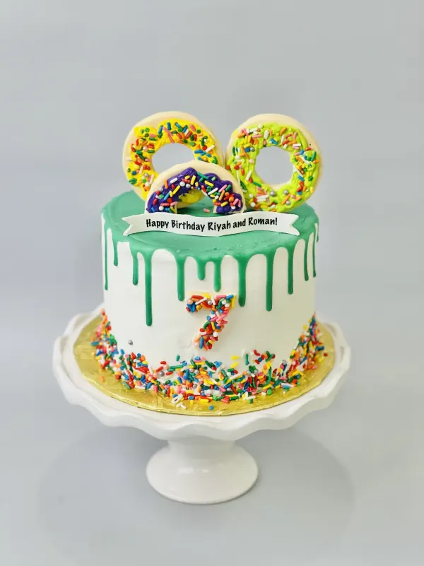 White drip cake with green ganache, sprinkle number cookies and Happy Birthday Riyah and Roman