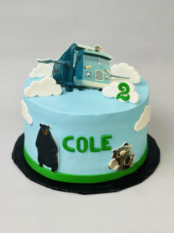 Blue trash truck birthday cake with fondant clouds, bear and raccoon cutouts and the name Cole