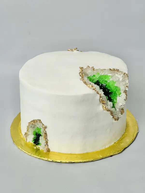White geode birthday cake with green and clear rock candy crystals and gold-painted edges