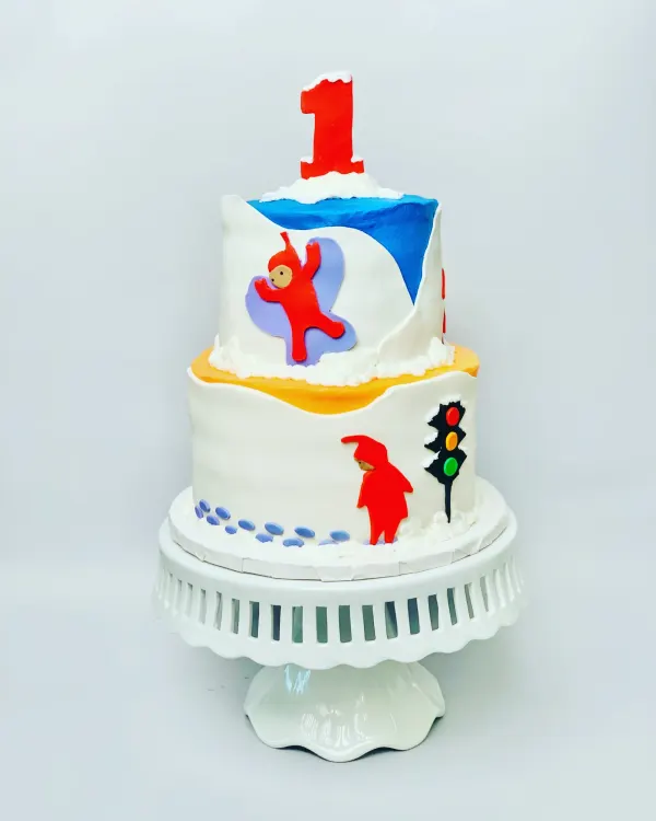 Two-tier snow scene cake with a child in a red snowsuit, a traffic light and red number 1 topper