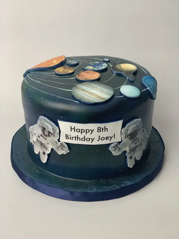 Navy solar system cake with fondant planets, astronaut cutouts and Happy 8th Birthday Joey