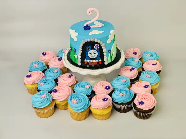 Thomas the Tank Engine cake with a tunnel scene, pink 2 topper and pink and blue rosette cupcakes