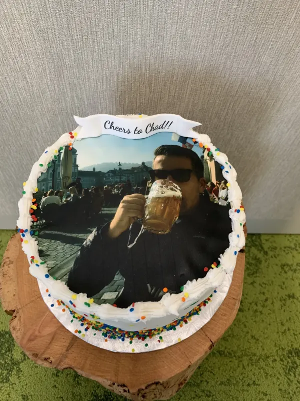 Round photo cake with a Cheers to Chad banner, edible beer-toast photo and rainbow sprinkles