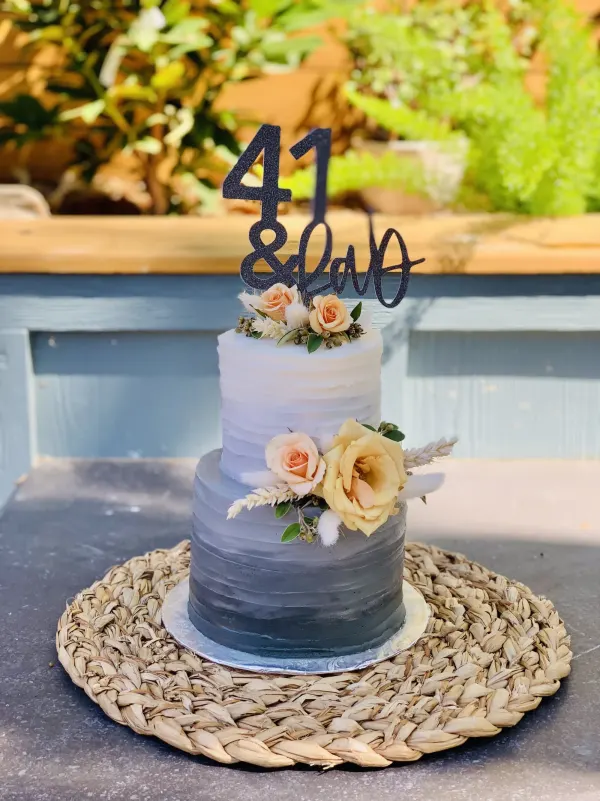 Two-tier grey ombre buttercream cake with fresh peach roses and a black 41 and Fab topper
