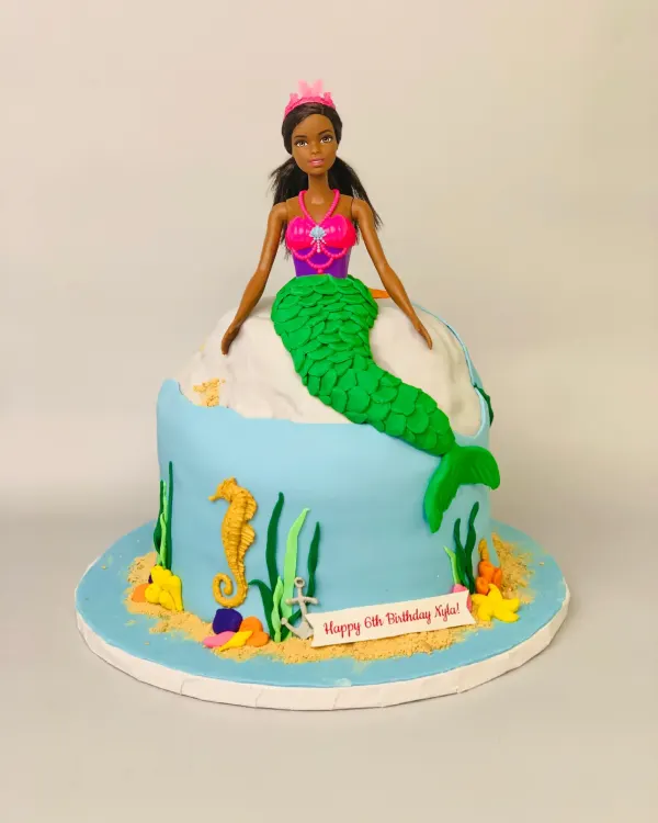 Mermaid doll cake with a green fondant scale tail, seahorse and Happy 6th Birthday Xyla banner