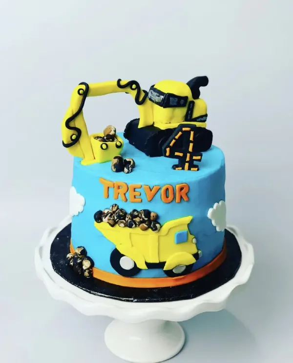 Construction birthday cake with a fondant excavator topper, dump truck and Trevor in orange