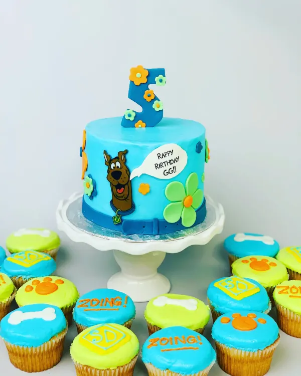 Scooby-Doo fifth birthday cake with a blue collar band plus bone, paw print and Zoing cupcakes