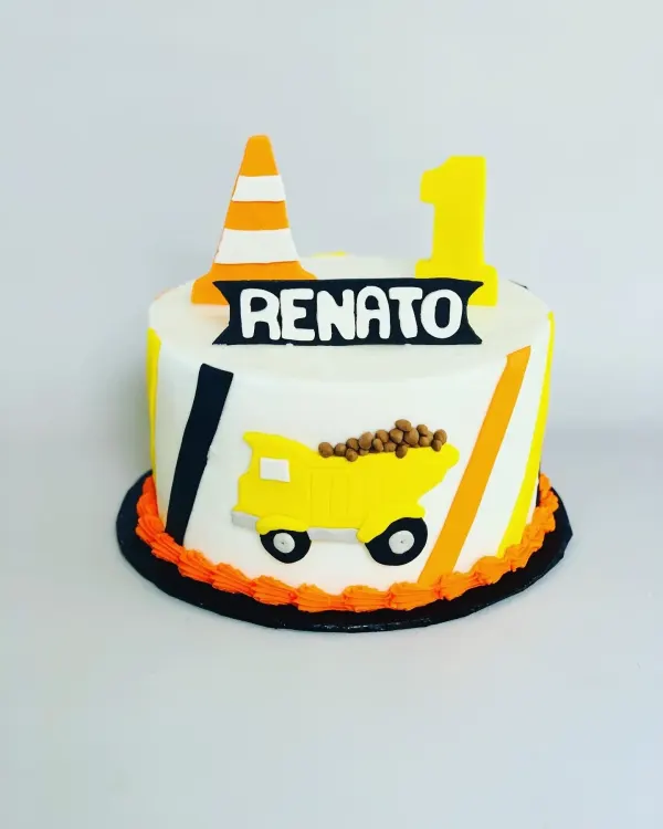 White construction cake with an orange traffic cone, yellow 1 and a Renato dump truck design