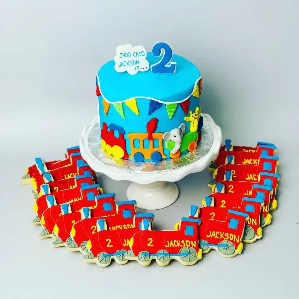 Blue train second birthday cake with a fondant animal train and red Jackson train cookies