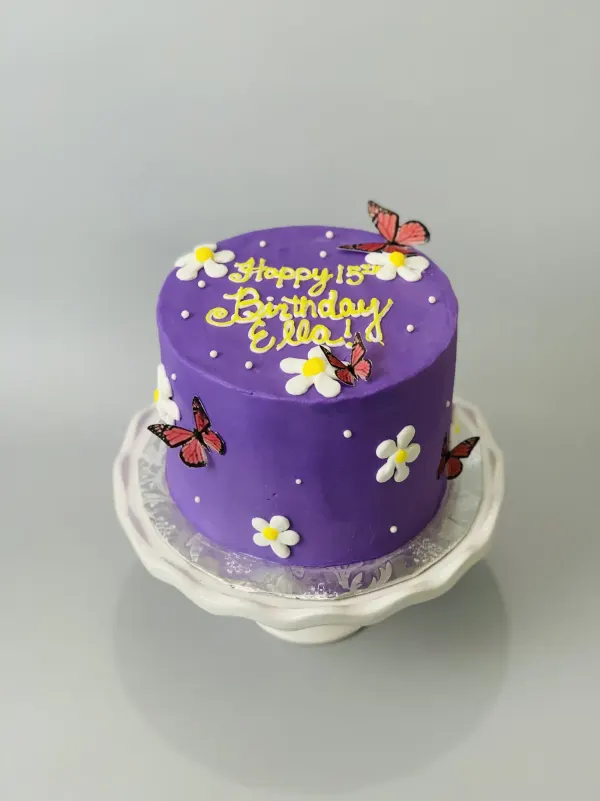Purple buttercream birthday cake with white daisies, butterflies and Happy 15th Birthday Ella