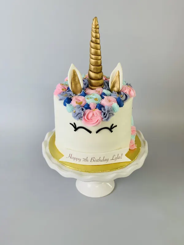 Unicorn birthday cake with a gold horn, pink and blue buttercream mane and Happy 7th Birthday Lyla