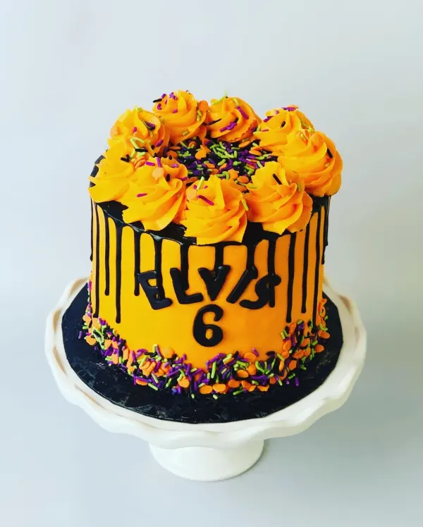 Orange buttercream drip cake with black chocolate drip, rosettes, sprinkles and Elvis 6 in black