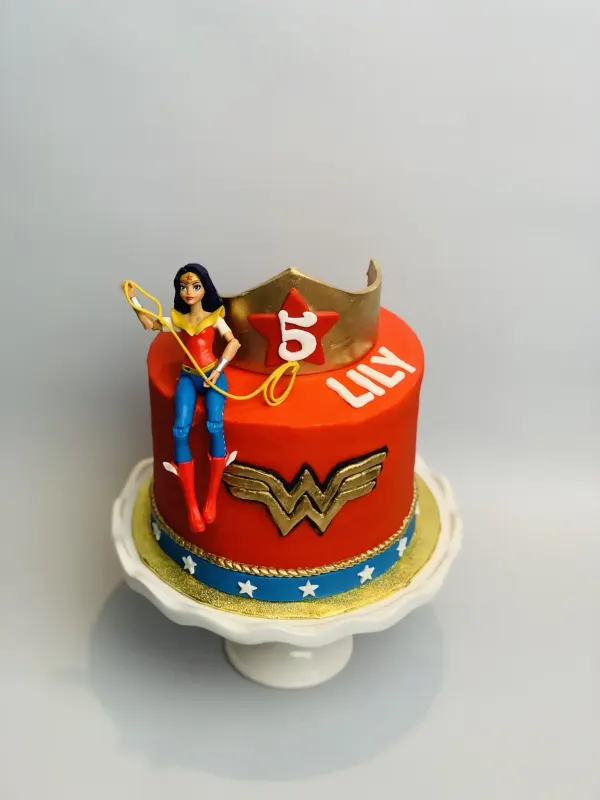 Wonder Woman birthday cake in red fondant with a gold logo, crown, doll topper and Lily 5