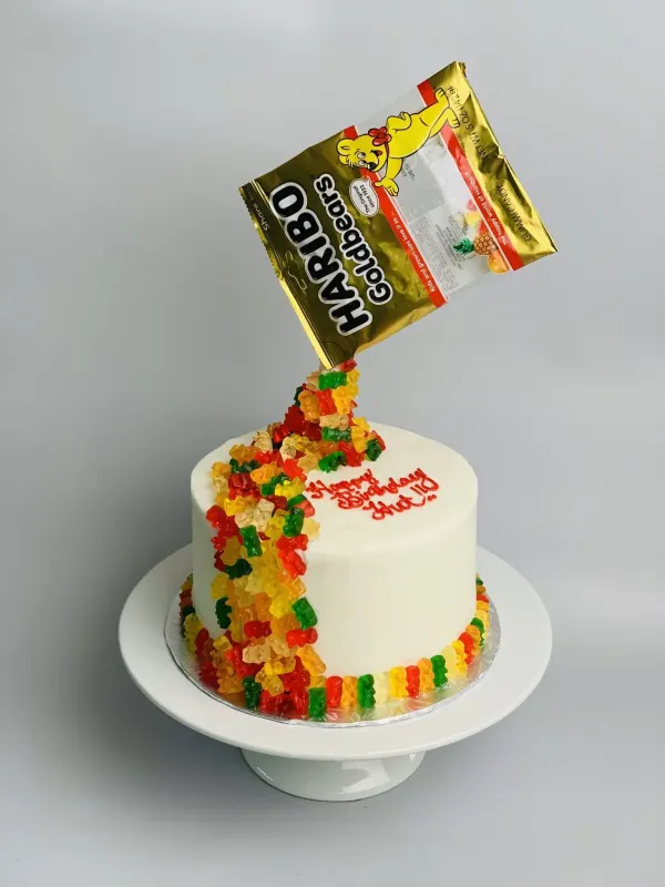 Anti-gravity birthday cake with a Haribo Goldbears bag pouring gummy bears down white buttercream