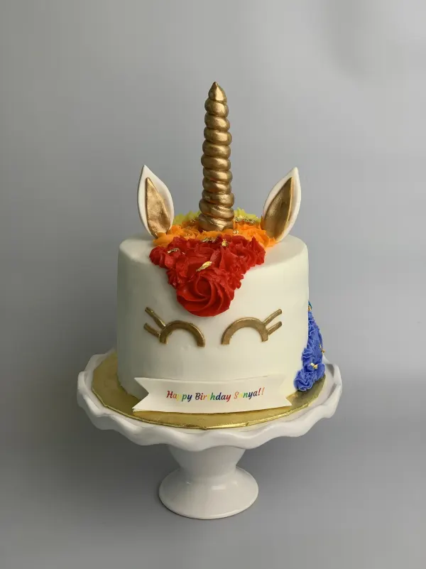 Unicorn birthday cake with a gold horn, rainbow buttercream mane and Happy Birthday Sonya banner