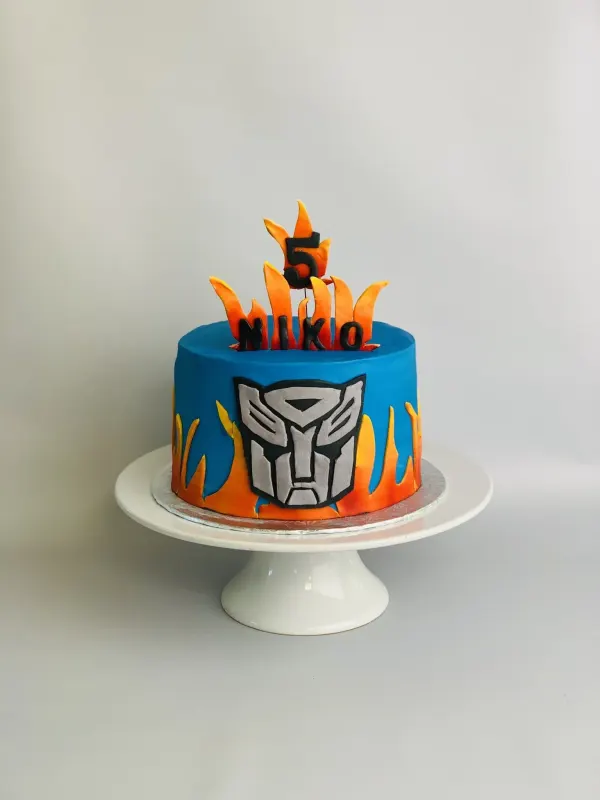 Transformers birthday cake with the Autobot emblem, fondant flames and a Niko 5 topper