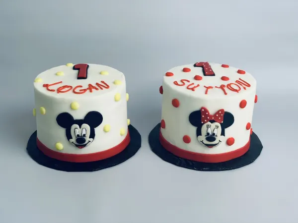 Pair of first birthday cakes with Mickey and Minnie Mouse faces, named Logan and Sutton