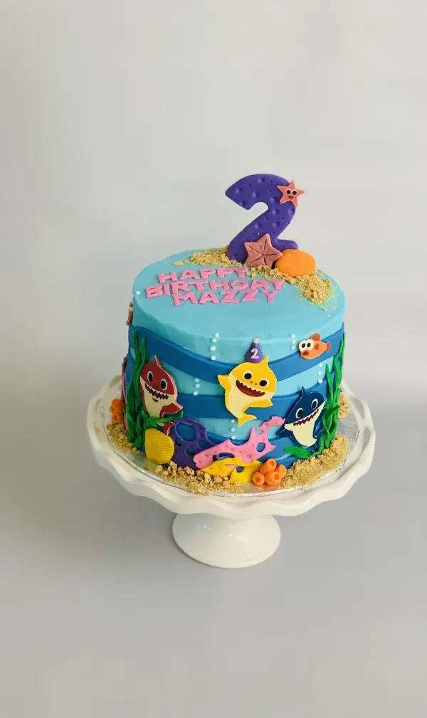 Baby Shark second birthday cake with coral, seaweed and Happy Birthday Mazzy in pink letters