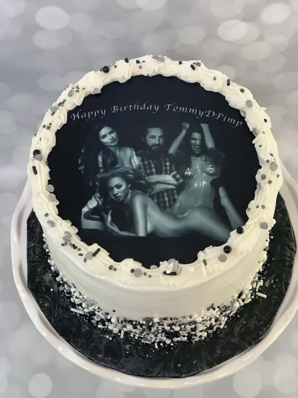 Round birthday cake with white buttercream, silver sprinkles and a black and white photo print topper