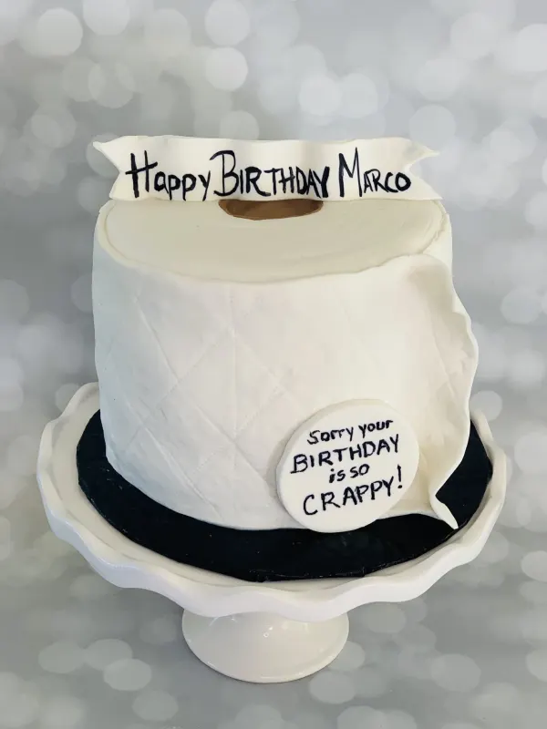Toilet paper roll birthday cake with a Happy Birthday Marco banner and a joke speech bubble