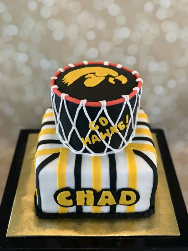 Two-tier Iowa Hawkeyes cake with a basketball hoop tier reading Go Hawks and Chad on a jersey base