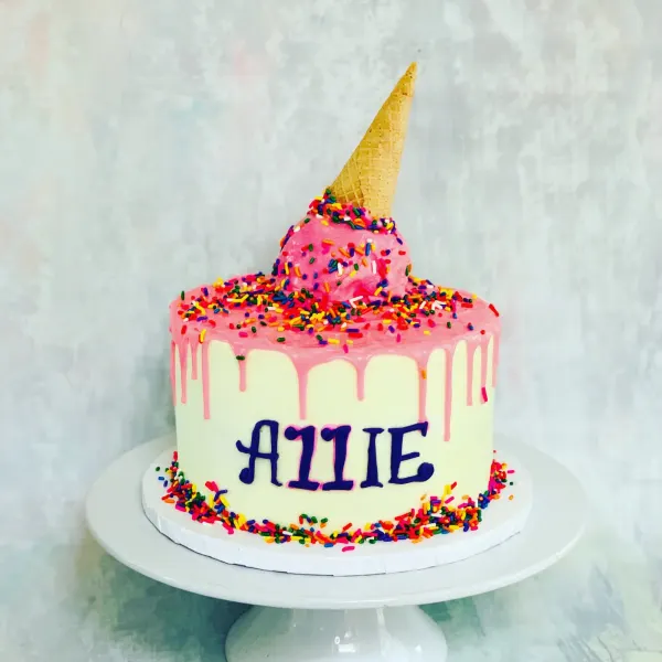 Ice cream cone birthday cake with pink drip, rainbow sprinkles and Allie piped in purple