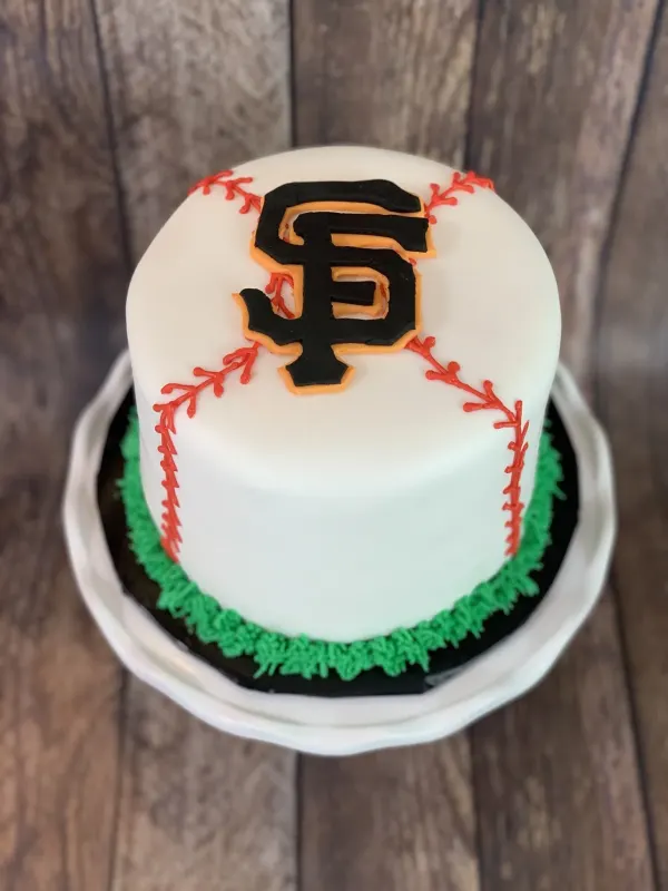 Baseball birthday cake with the SF Giants logo, red stitching and a piped green grass base