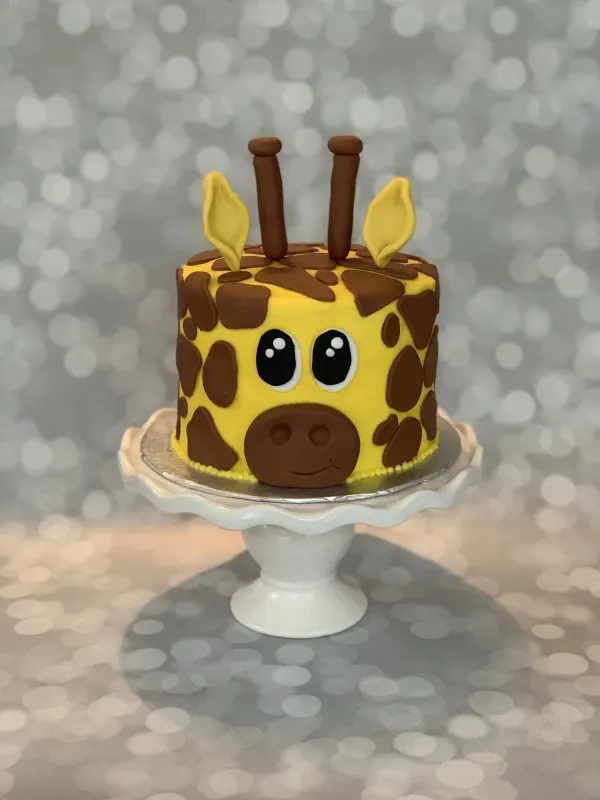 Giraffe face birthday cake with brown fondant spots, horns and yellow ears