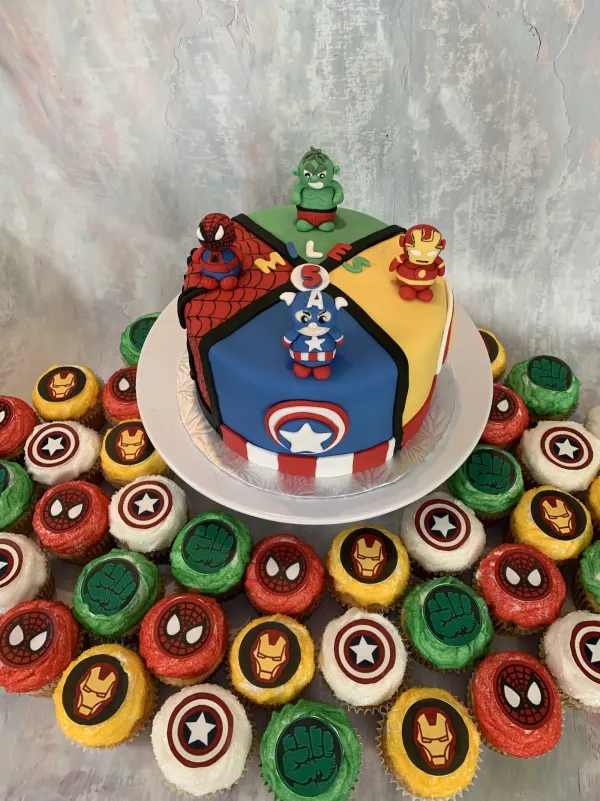 Avengers cake split into four hero panels with Miles 5, ringed by superhero logo cupcakes