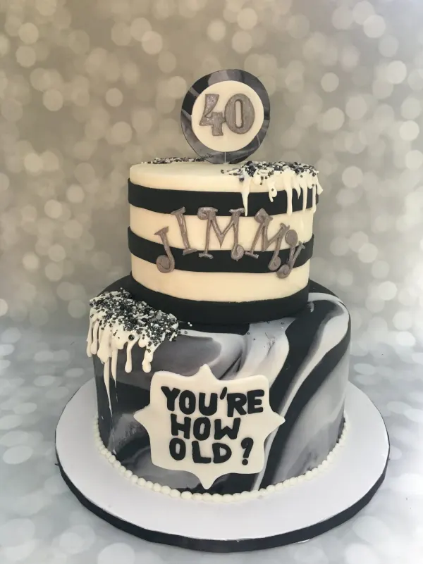 Two-tier black and white 40th cake with a marbled tier and JIMMY spelled in music notes