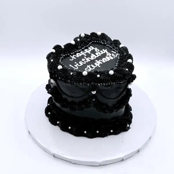 All black cake with black Lambeth piping and white pearls, lettered Happy Birthday Stephanie