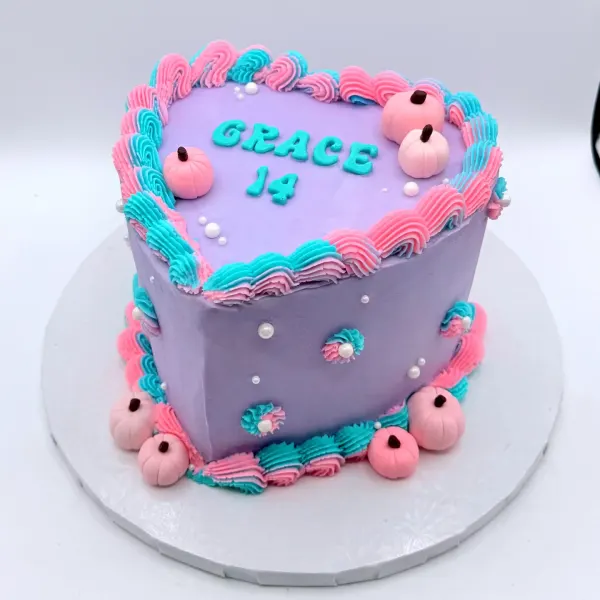Purple cake with pink and teal piped ruffles, small pink fondant pumpkins and Grace 14 lettered