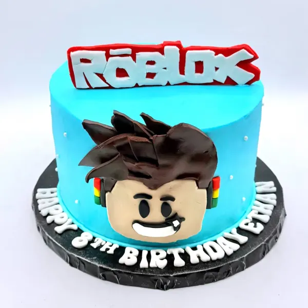 Blue cake with a Roblox logo topper, a blocky character face and a dark textured base band