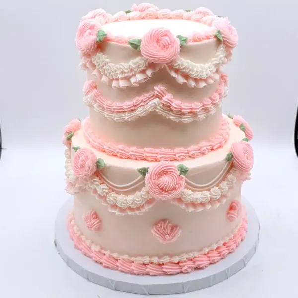 Two tier blush cake with Lambeth piping, piped roses, swags and drop strings