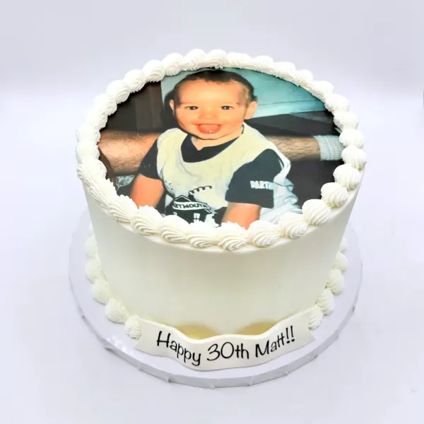 White cake with an edible photo print of a child, piped shell borders and Happy 30th Matt