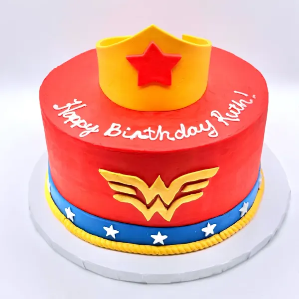 Red cake with a gold tiara topper, a gold winged emblem and a blue band of white stars